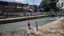 Anak-anak bermain di sekitar Kali Sentiong, Kecamatan Johar Baru, Rabu (22/9/2021). Pengerukan lumpur Kali Sentiong sekaligus mencegah banjir di kawasan tersebut yang kerap terjadi saat musim hujan. (merdeka.com/Iqbal S. Nugroho)