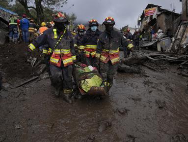 Petugas membawa jenazah korban banjir bandang yang dipicu oleh hujan yang memenuhi aliran sungai terdekat yang merusak mekanisme penahanan dan meruntuhkan lereng bukit dan membawa gelombang lumpur ke rumah-rumah di daerah La Gasca di Quito, Ekuador, Selasa (1/2/2022). (AP Photo/Dolores Ochoa)