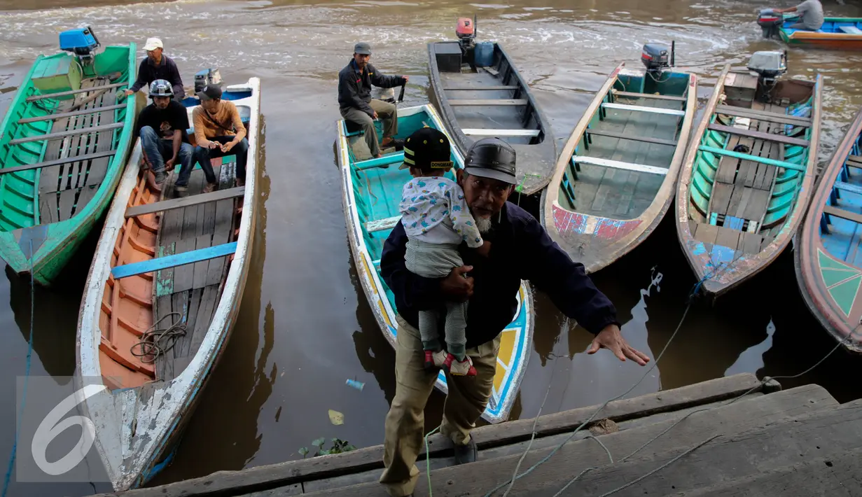 Pria menggendong anaknya turun dari perahu sampan di Sungai Kapuas, Pontianak, Kalimantan Barat, Sabtu (22/8/2015). Perahu Sampan saat ini masih diminati warga sebagai pilihan moda transportasi sederhana di Sungai Kapuas. (Liputan6.com/Faizal Fanani)
