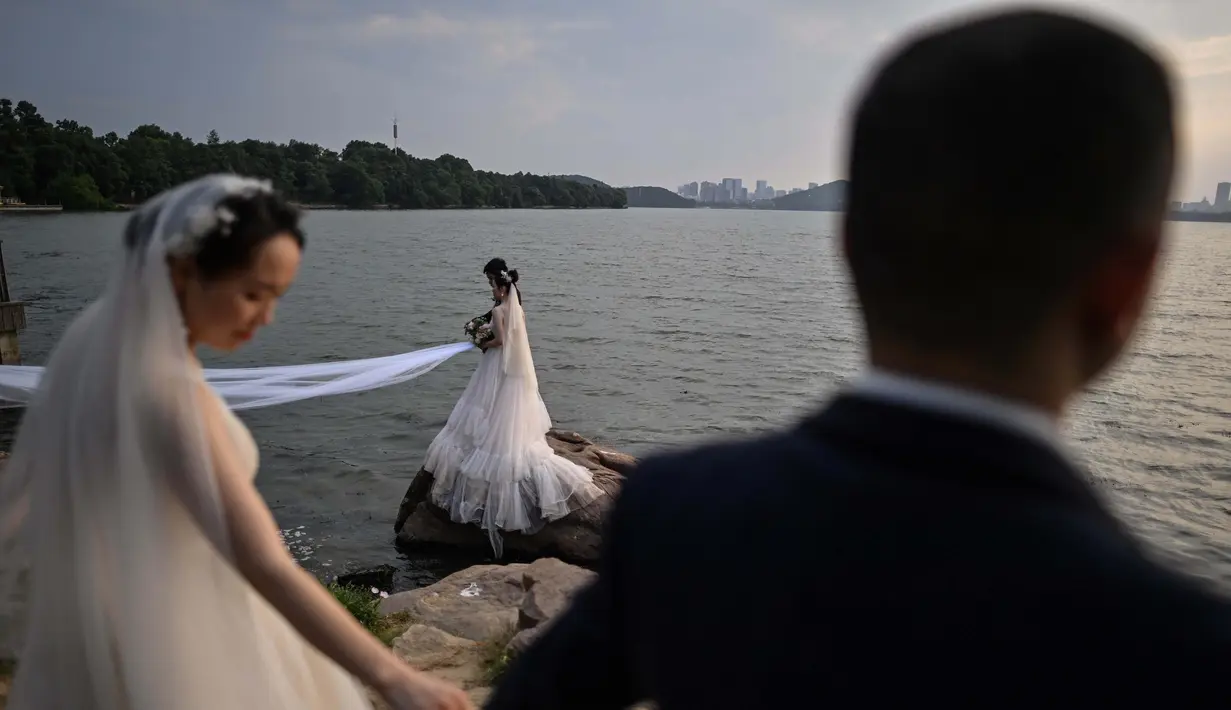 Pasangan berpose saat sesi pemotretan pernikahan di sebelah East Lake, Wuhan, Provinsi Hubei, China, 5 Agustus 2020. Pencabutan karantina 76 hari di Wuhan terkait COVID-19 pada April lalu membawa kehidupan dan lalu lintas kembali macet. (Hector Retamal/AFP)