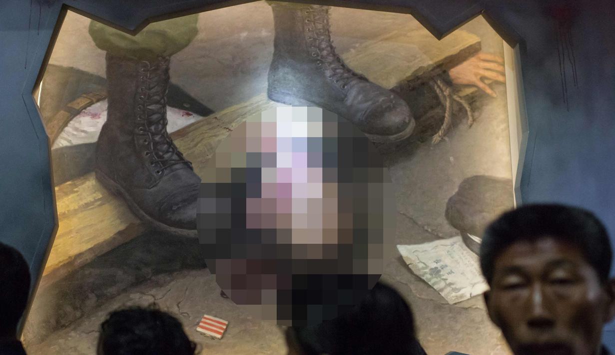 Pengunjung melewati lukisan yang menunjukkan tentara AS menyiksa seorang pria Korea Utara, di Museum Sinchon of the American War Atrocities di Pyongyang 24 Juli 2017. (AFP Photo/Ed Jones)