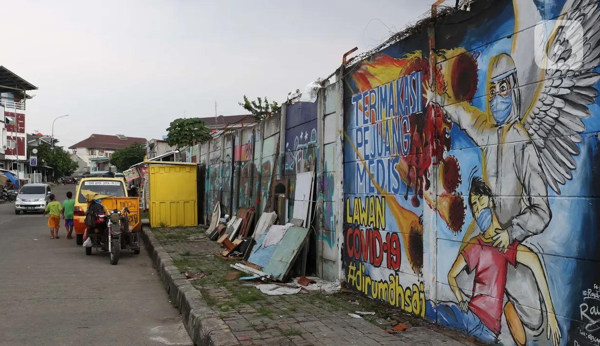 Warga melintasi mural ajakan melawan COVID-19 di Depok, Jawa Barat, Selasa (14/4/2020). Pemprov Jawa Barat akan memulai pembatasan sosial skala besar di Bogor, Depok, Bekasi pada Rabu (15/4) dengan menyiapkan anggaran Rp4 triliun sebagai jaring pengaman sosial. (Liputan6.com/Helmi Fithriansyah)