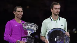 Rafael Nadal dari Spanyol (kiri) memegang trofi usai mengalahkan Daniil Medvedev dari Rusia dalam final tunggal putra Tenis Australia Open 2022 di Melbourne, Minggu (31/1/2022). Nadal menjadi petenis pertama yang sukses menjuarai level Grand Slam sebanyak 21 kali. (AP Photo/Andy Brownbill)