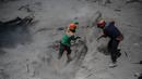 Tim penyelamat melakukan pencarian korban di rumah yang terkubur abu vulkanik letusan Gunung Semeru di Desa Sumber Wuluh, Lumajang, Jawa Timur, Selasa (7/12/2021). Letusan Gunung Semeru menewaskan sedikitnya 34 orang. (AFP/Juni Kriswanto)