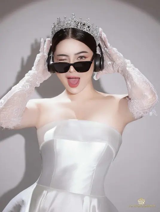 Penampilannya dilengkapi dengan aksesori seperti mahkota, headphone, dan kacamata hitam. [@felicyangelista_].