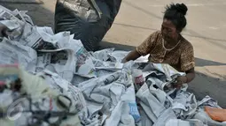Seorang ibu dengan cekatan merapikan lembaran-lembaran koran sisa alat salat Id di wilayah Jatinegara, Jakarta, Rabu (6/7/2016). Sisa koran alas salat menjadi berkah tersendiri bagi pengumpul koran bekas. (Liputan6.com/Yoppy Renato)