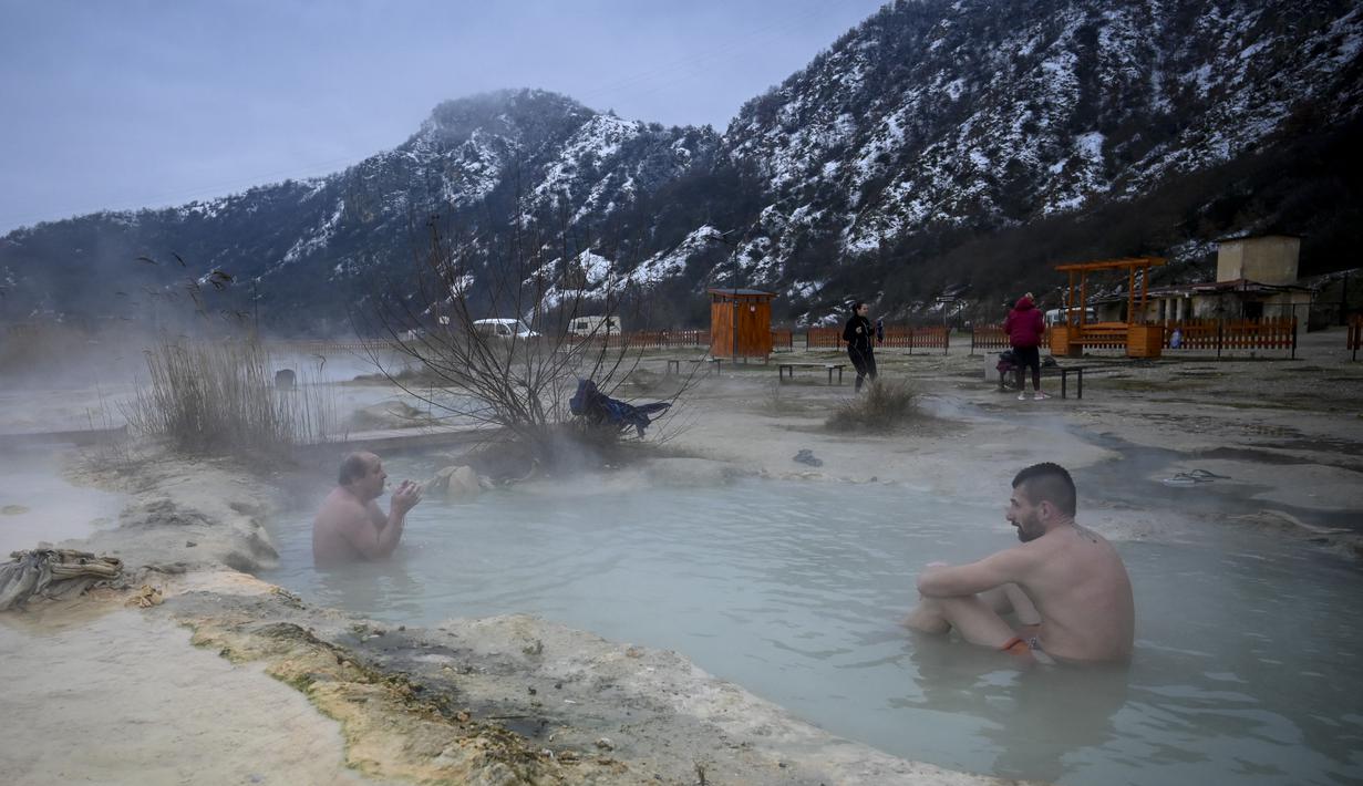 Orang-orang menikmati air panas di mata air mineral alami pada hari musim dingin di dekat desa Rupite, Bulgaria (2/2/2022). Penduduk setempat percaya bahwa air mineral menyembuhkan banyak penyakit dan gangguan. (AFP/Nikolay Doychinov)