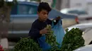 Seorang anak menjual sayuran untuk membantu keluarga mereka menghasilkan sedikit uang selama bulan suci Ramadhan di Gaza (19/5/2019). Umat Muslim di seluruh dunia tengah melaksanakan puasa dimana mereka tidak makan, minum mulai dari matahari terbit hingga terbenam. (AP Photo/Hatem Moussa)