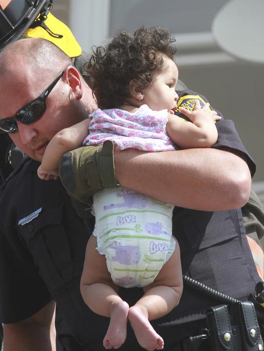 Seorang polisi Hazleton menggendong seorang bayi setelah kebakaran terjadi di sebuah gedung apartemen di Hazleton, Pennsylvania (26/7/2019). Pemadam kebakaran kota menggunakan truk menyelamatkan penghuni dari lantai tiga gedung. (Warren Ruda/Hazleton Standard-Speaker via AP)