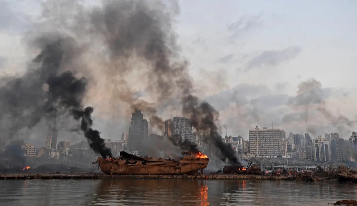 Sebuah kapal besar yang terbakar setelah ledakan besar di pelabuhan Kota Beirut, Lebanon (5/8/2020). Kapal besar tersebut terangkat ke daratan setelah dua ledakan besar menghantam Beirut pada Selasa (4/8/2020) lalu. (AFP Photo)