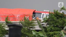 Petugas mengecek kereta ringan lintas rel terpadu (LRT) Jabodebek yang mengalami kecelakaan di jalur lintas LRT Cibubur, Jakarta Timur, Senin (25/10/2021). Petugas terlihat ada di rel untuk membantu proses evakuasi di mana bagian gerbong kereta ditutup terpal. (Liputan6.com/Herman Zakharia)