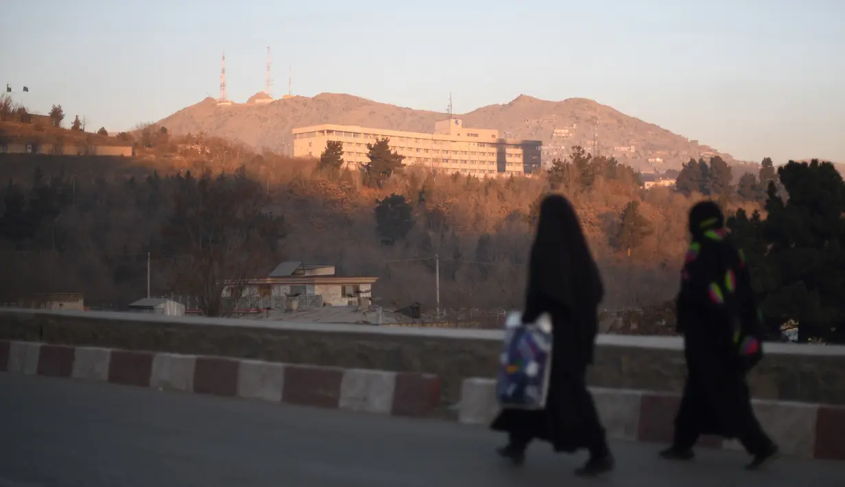 Dua wanita Afghanistan berjalan melewati Hotel Intercontinental setelah sebuah serangan di Kabul pada Senin (21/1). Kelompok bersenjata membunuh setidaknya lima orang dan melukai delapan lainnya. (SHAH MARAI/AFP)