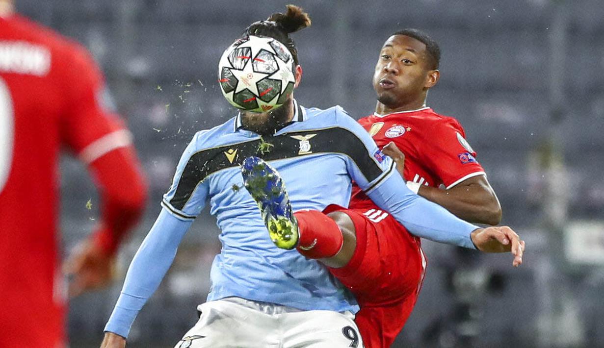 Pemain Bayern Munchen, David Alaba, berebut bola dengan pemain Lazio, Vedat Muriqi, pada laga Liga Champions di Allianz Arena, Kamis (18/3/2021). Bayern Munchen menang dengan skor 2-1. (AP Photo/Matthias Schrader)