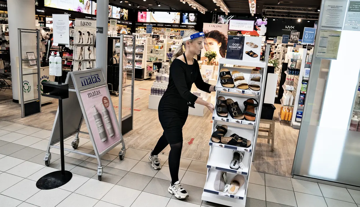 Seorang perempuan meletakkan rak sepatu di luar toko di Aalborg Storcenter di Aalborg, Denmark saat pertokoan dibuka kembali, pada Rabu (21/4/2021). Denmark membuka kembali berbagai aktivitas ekonomi negaranya setelah kasus infeksi Covid-19 mengalami penurunan. (Henning Bagger/Ritzau Scanpix via AP)
