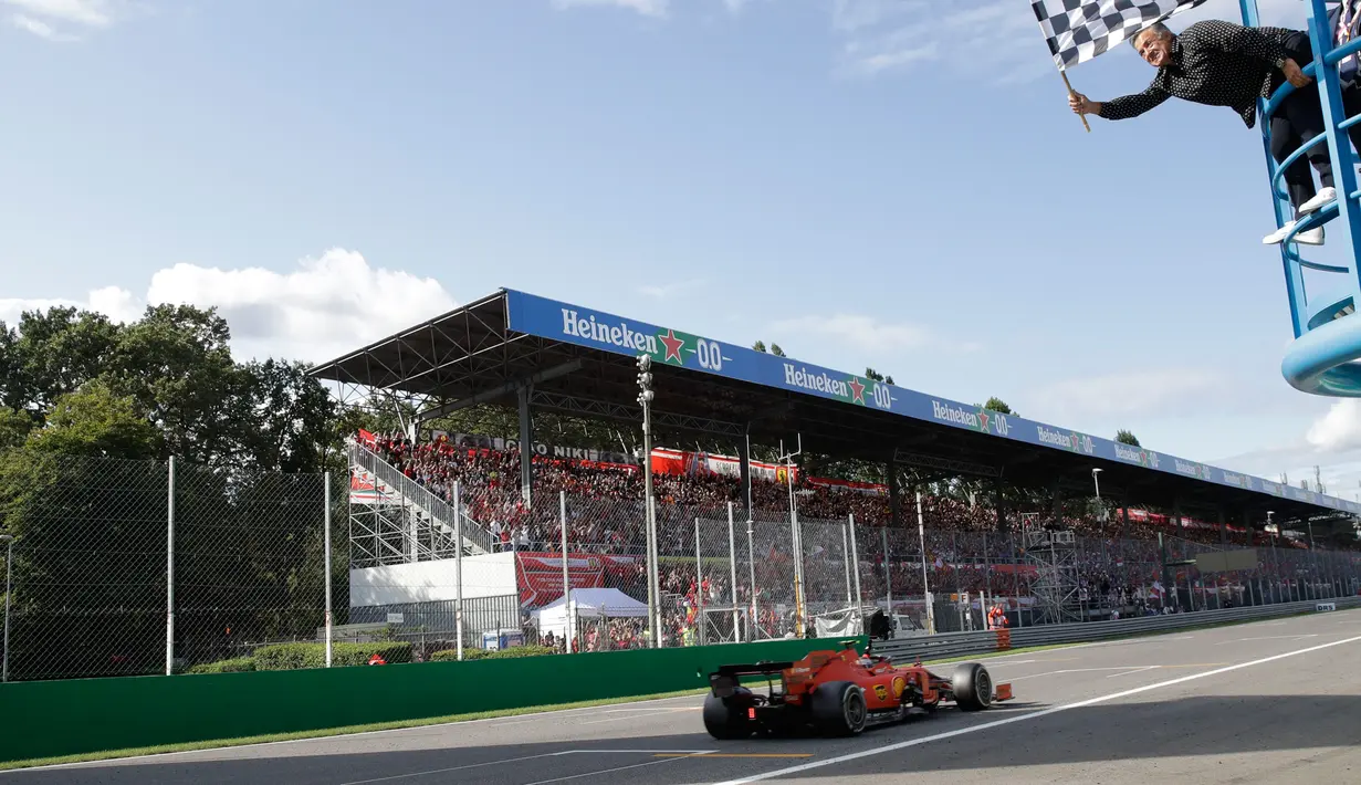 Mantan pembalap F1 Jean Alesi mengibarkan bendera kotak-kotak ketika pembalap Ferrari Charles Leclerc melintasi garis finis selama F1 GP Italia 2019 di Sirkuit Monza, Minggu (8/9/2019). Leclerc juara setelah pertarungan alot melawan Lewis Hamilton dan Valtteri Bottas. (AP Photo/Pool/Luca Bruno)