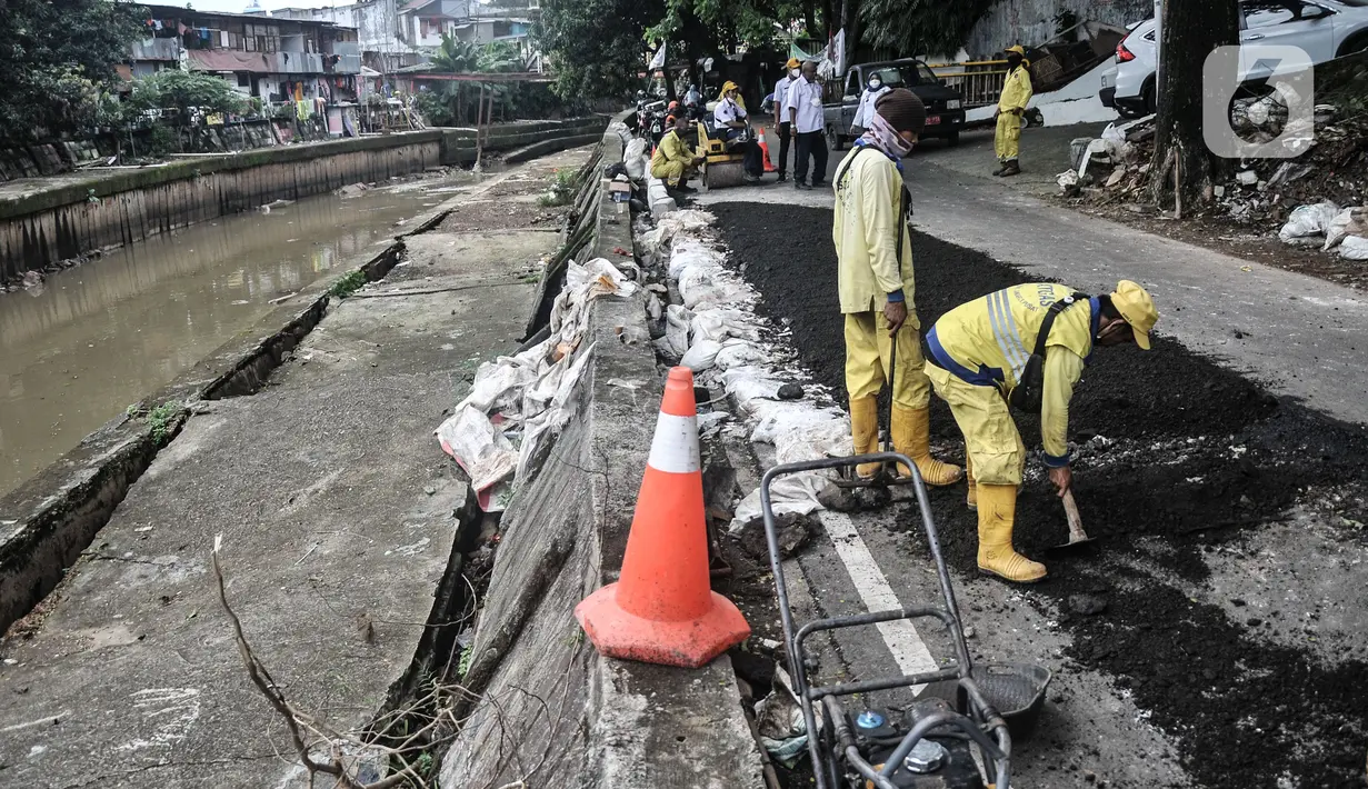 Petugas Sudin Bina Marga Jakarta Pusat memperbaiki jalan ambles di Jalan Inspeksi Kali Ciliwung, Kenari, Rabu (19/1/2022). Jalan yang berada di belakang RSCM tersebut ambles sepanjang 40 meter akibat terkikis oleh hujan deras kemarin sehingga menyulitkan akses warga. (merdeka.com/Iqbal S Nugroho)