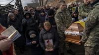 Kerabat dan teman berkabung di pemakaman sersan polisi senior Roman Rushchyshyn di desa Soposhyn, pinggiran Lviv, Ukraina barat, Kamis, 10 Maret 2022. Rushchyshyn, seorang anggota Batalyon Patroli Polisi Khusus Lviv, terbunuh di Wilayah Luhansk. (AP Photo/Bernat Armangue)