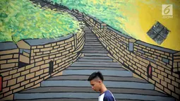 Seorang pria berjalan di Kampung Warna Warni Lubuklinggau, Sumatera Selatan, Rabu (10/1). Saat ini kampung tersebut telah disulap menjadi tempat wisata baru di Lubuklinggau. (Liputan6.com/Immanuel Antonius)
