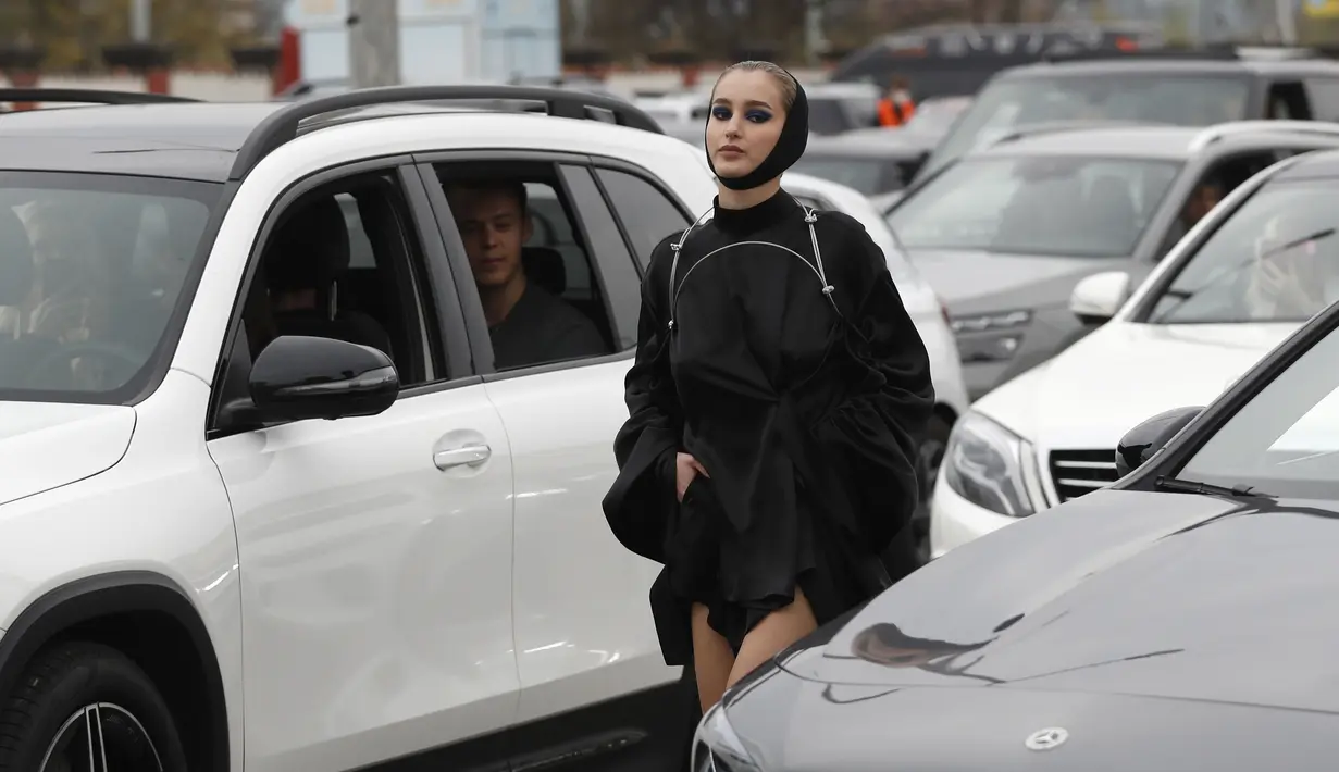 Seorang model berjalan melewati mobil saat drive-in fashion show bagian dari Praha Fashion Week di Praha, Republik Ceko, Sabtu (1/5/2021). Karena pembatasan virus corona, penonton hanya dapat melihat pertunjukan dari dalam mobil mereka. (AP Photo/Petr David Josek)