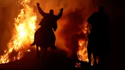 Seorang pria menunggangi kuda melewati api unggun saat festival Luminarias di San Bartolome de Pinares, Spanyol, Jumat (16/1/2020). Festival keagamaan itu sebaga bagian dari ritual untuk menghormati San Antonio Abad (Santo Anthony), santo pelindung binatang. (AP Photo/Manu Fernandez)