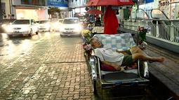 Pengemudi becak tidur siang di luar pusat perbelanjaan di Penang (1/8/2020). Malaysia tengah memperingatkan gelombang kedua virus corona COVID-19. (AFP Photo/Goh Chai Hin)
