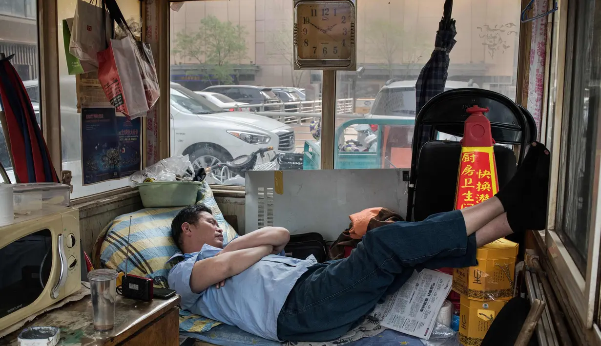 Seorang petugas parkir beristirahat selama jam makan siang di Beijing (18/4). Beijing adalah ibu kota Republik Rakyat Tiongkok dan merupakan salah satu kota terpadat di dunia. (AFP Photo/Nicolas Asfouri)