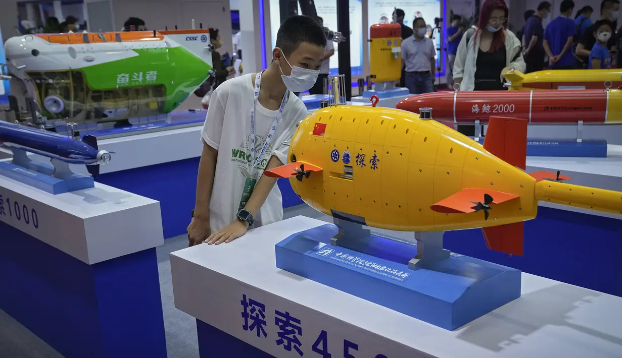 Seorang anak yang mengenakan masker melihat lebih dekat model kapal selam tak berawak buatan China yang dipamerkan di Konferensi Robot Dunia di Pusat Konferensi dan Pameran Internasional Yichuang di Beijing, Kamis (18/8/2022). (AP Photo/Andy Wong)