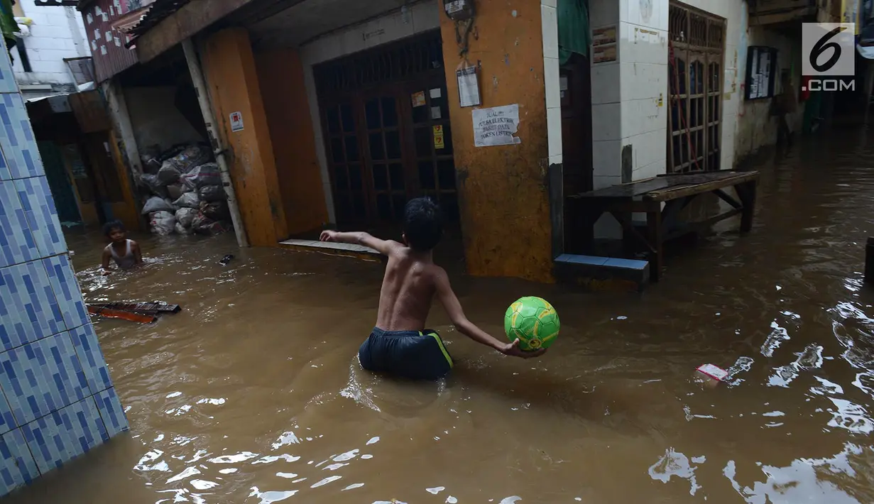 Anak-anak bermain saat banjir merendam permukiman di Kebon Pala, Jatinegara, Jakarta, Selasa (26/2/2019). Banjir setinggi 1,5 meter tersebut terjadi karena air Sungai Ciliwung meluap akibat air kiriman dari Bogor, Jawa Barat. (Merdeka.com/Imam Buhori)