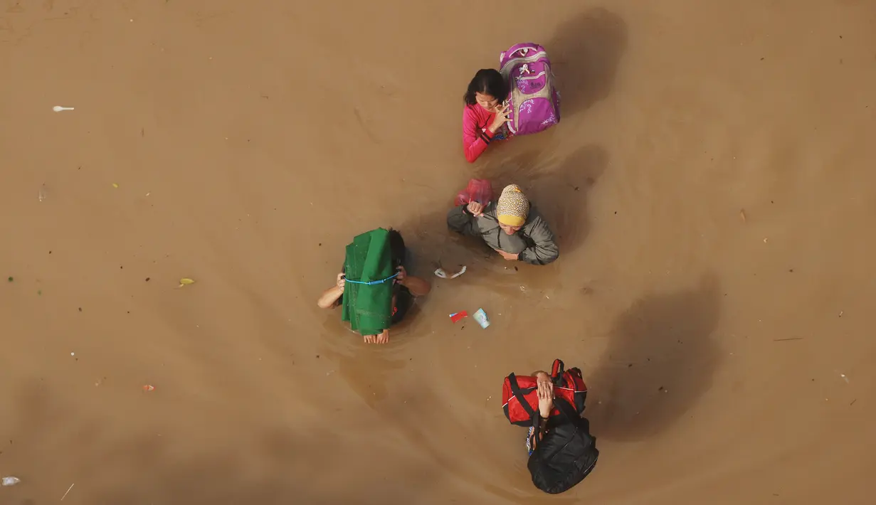 Warga menembus banjir yang merendam kabupaten Bandung, Jawa Barat, Minggu (13/3). Kawasan Bandung Selatan kembali dilanda banjir akibat luapan Sungai Citarum dan membuat lebih dari 3000 jiwa mengungsi. (Timur Matahari/AFP)