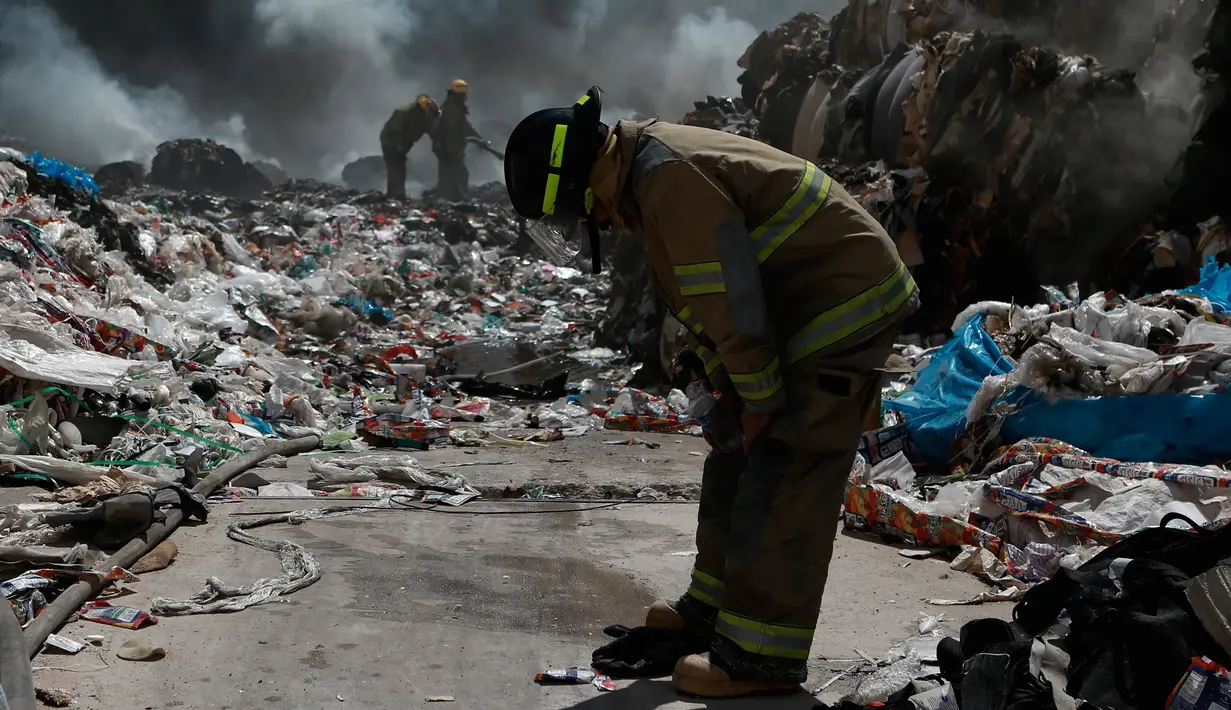 Seorang pemadam kebakaran beristirahat saat memadamkan api di pabrik daur ulang sampah di Ciudad Juarez, Meksiko (2/5). Pemerintah setempat menyarankan untuk tetap tinggal di dalam rumah dan menutup jendela serta pintu. (AP/Christian Torres)