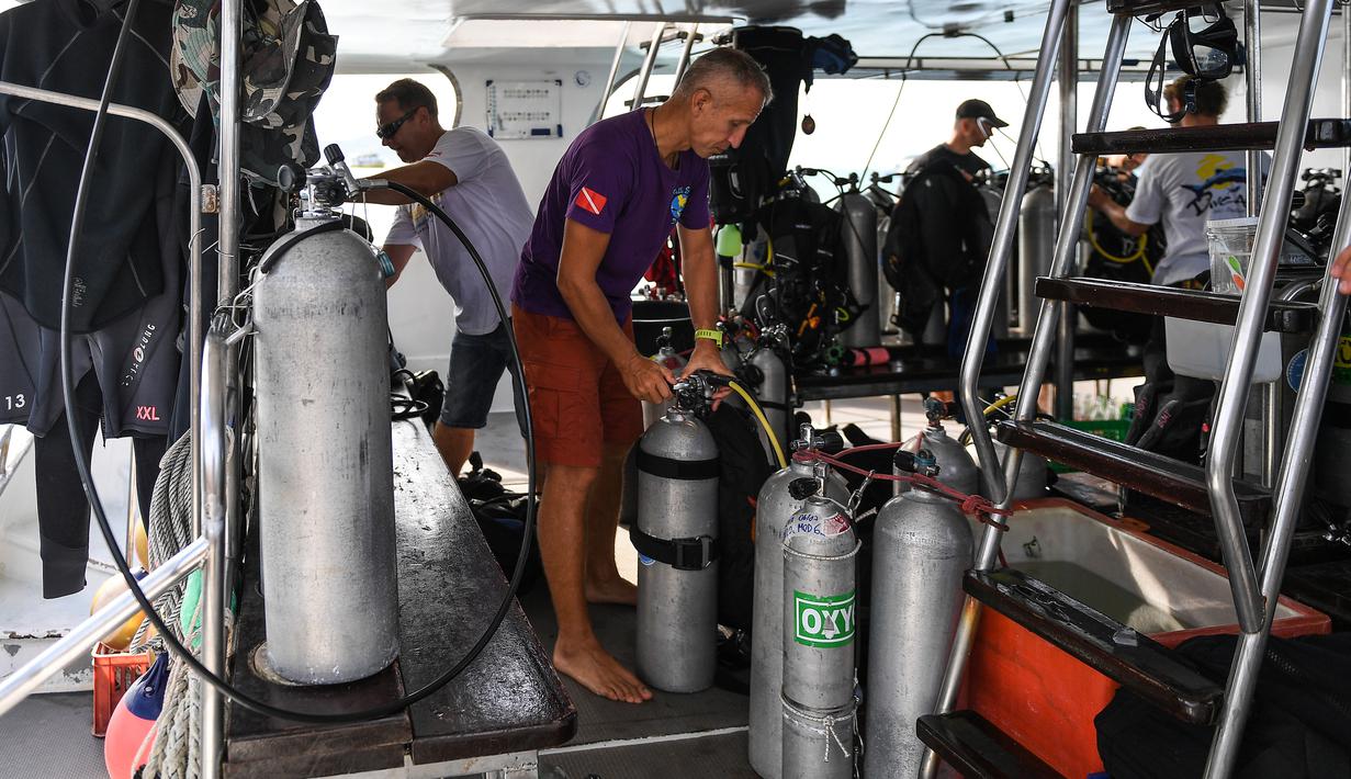 Penyelam memeriksa tangki oksigen saat bersiap melanjutkan pencarian korban kapal wisata yang terbalik di dermaga Chalong, Phuket, Sabtu (7/7). Sebanyak 56 penumpang dilaporkan hilang pada Jumat pagi sebelum upaya penyelamatan dimulai. (AFP/Mohd RASFAN)
