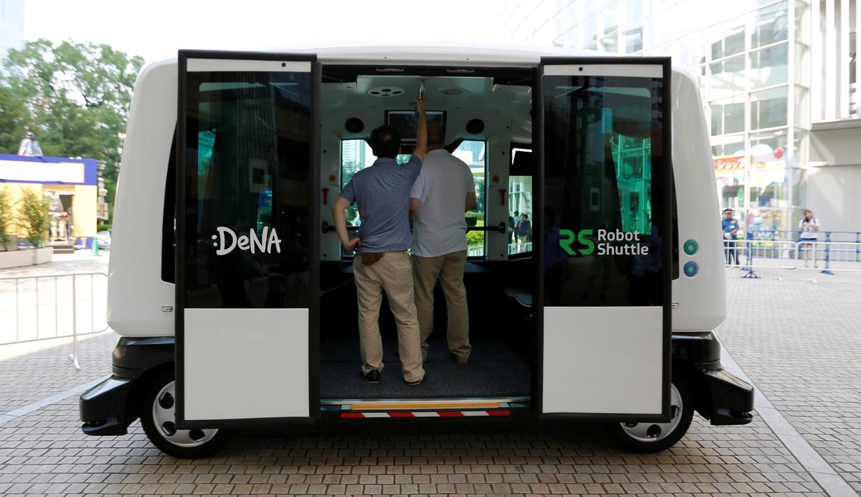 Dua orang lelaki mencoba menaiki Robot Shuttle saat didemonstrasikan di Tokyo, Jepang, Kamis (7/7). Dengan panjang hanya 4 meter, bus ini mampu menampung hingga 12 orang. (REUTERS / Toru Hanai)