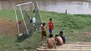 Anak-anak beristirahat usai bermain sepak bola di bantaran Kanal Banjir Barat, Jakarta, Jumat (5/4). Tidak adanya lapangan menjadikan lokasi tersebut sebagai tempat bermain mereka, meskipun dalam kondisi seadanya. (Liputan6.com/Immanuel Antonius)