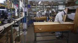 Pekerja menyelesaikan pembuatan peti mati di sebuah perusahaan di Ris Orangis, Prancis, Selasa (14/4/2020). Hingga saat ini, Prancis secara resmi mencatat lebih dari 15 ribu kematian akibat infeksi virus corona COVID-19. (AP Photo/Rafael Yaghobzadeh)