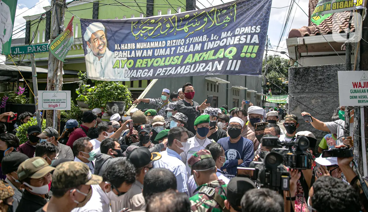 Anggota FPI mengadang anggota Polda Metro Jaya saat ingin memberikan surat pemanggilan kepada Rizieq Shihab di kediamannya di kawasan Petamburan, Jakarta, Rabu (2/12/2020). Polisi kembali memanggil Rizieq Shihab terkait acara Maulid Nabi dan resepsi putrinya. (Liputan6.com/Faizal Fanani)