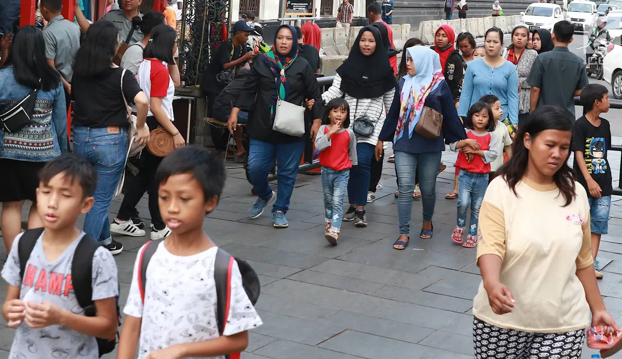 Pejalan kaki melintasi jalur masuk dan keluar Taman Fatahilah saat uji coba simulasi di kawasan Kota Tua, Jakarta, Selasa (23/4). Penataan akses tersebut dilakukan untuk memperlancar keluar masuknya pengunjung ke kawasan wisata tersebut. (Liputan6.com/Immanuel Antonius)