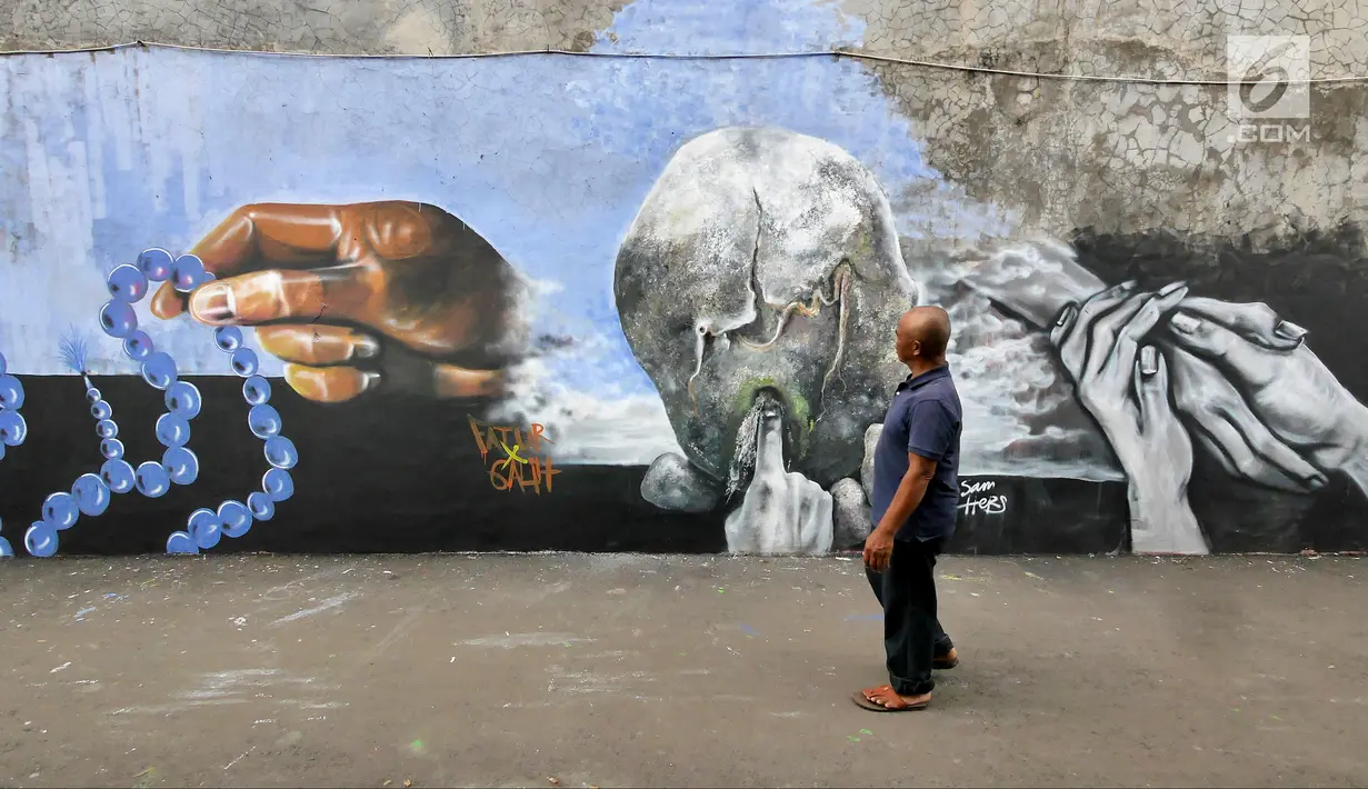 Seorang warga melihat mural bertema Islami di Gang Abdul Jabar, Jagakarsa, Jakarta, Senin (28/5). (Liputan6.com/Herman Zakharia)