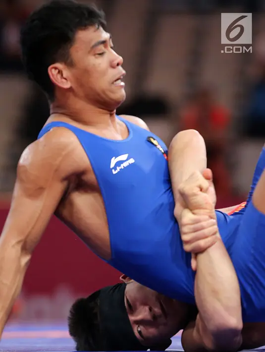 Pegulat China Zhang Gaoquan mengunci Muhammad Aliansyah dari Indonesia saat bertarung pada kelas putra 67 Kg Asian Games 2018 di arena gulat JCC Senayan, Selasa (21/8). Aliansyah kalah atas lawanya dengan skor 0-7. (Liputan6.com/Fery Pradolo)