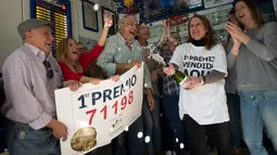 Penjual tiket undian dan pemenang merayakan kemenangan di sebuah toko lotre di Malaga, Spanyol (22/12). Sebanyak 22 orang karyawan di panti wreda itu menang hadiah utama lotre Natal tahunan Spanyol. (AFP Photo/Jorge Guerrero)