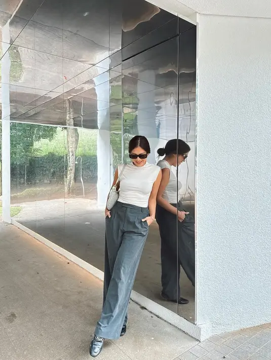 Atau gaya Tyna Dwi Jayanti memadukan atasan putih tanpa lengan dengan celana panjang abu-abu, dan sunglasses. [Foto: Instagram/tynadwijayanti]