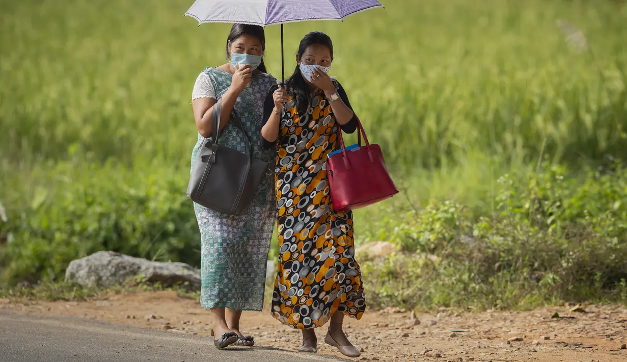 Wanita etnis Khasi dengan pakaian tradisional mengenakan masker berjalan di desa Umwang, di sepanjang perbatasan negara bagian Assam-Meghalaya, India, Rabu (27/10/2021). Lebih dari 60 persen dari 1,3 miliar warga India bertani. (AP Photo/Anupam Nath)
