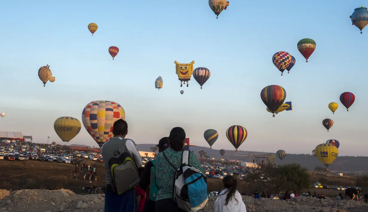 Warga melihat balon udara yang menghiasi langit di Cajititlan, Meksiko, Minggu (7/5).  Festival balon udara ini menjadi tontonan menarik bagi warga sekitar dan wisatawan. (AFP PHOTO / Hector Guerrero)