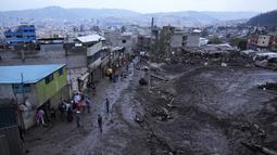 Orang-orang bergabung dengan petugas penyelamat untuk mencari korban dalam reruntuhan sehari setelah lereng bukit yang diguyur hujan runtuh dan membawa gelombang lumpur ke rumah dan lapangan olahraga, di lingkungan La Gasca di Quito, Ekuador, Rabu (2/2/2022). (AP Photo/Dolores Ochoa)