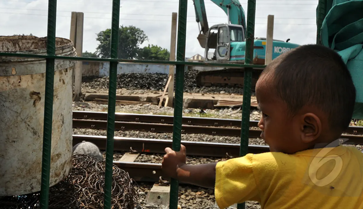 Seorang bocah melihat ekskavator di pinggir rel kereta api. Orangtua mereka memilih bertahan di kasan Bongkaran karena tak punya uang untuk menyewa rumah, Tanah Abang, Jakarta, Rabu (21/1/2015). (Liputan6.com/Miftahul Hayat)