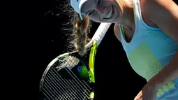 Petenis Denmark, Caroline Wozniacki tertawa ketika rambutnya tersangkut di raket pada sesi latihan menjelang Grand Slam Australia Terbuka di Melbourne, Minggu (14/1). Grand slam tersebut bakal berlangsung 15-28 Januari 2018. (AP/Vincent Thian)