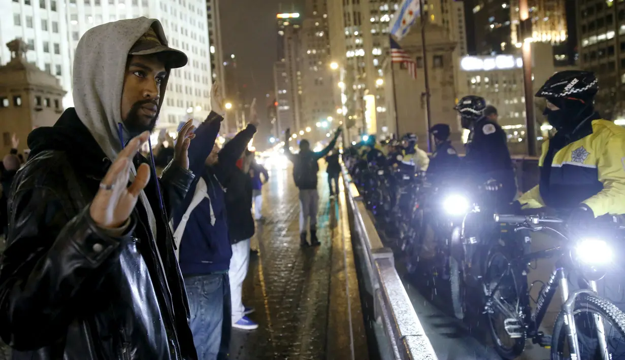 Pengunjuk rasa menghadapi polisi saat aksi protes di Chicago, Illinois, Rabu (25/11). Ketegangan rasial memanas setelah rilisnya video seorang polisi kulit putih menembak remaja kulit hitam, Laquan McDonald (17) pada Oktober 2014. (REUTERS/Andrew Nelles)