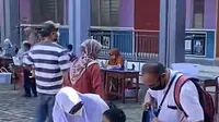 Sepasang orangtua di Malaysia antar anaknya pada hari pertama sekolah dengan menggunakan seragam, sebagai bentuk motivasi bersekolah untuk anaknya. (Dok. Screenshot TikTok @kosmoonline)