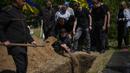 Iuliia Loseva (tengah) melemparkan tanah ke atas peti mati suaminya Volodymyr Losev (38) selama pemakamannya di sebuah pemakaman di Zorya Truda, wilayah Odesa, Ukraina, Senin, 16 Mei 2022. Volodymyr Losev, seorang tentara relawan Ukraina, tewas pada 7 Mei lalu ketika kendaraan militer yang dikendarainya menabrak sebuah ranjau di Ukraina timur. (AP Photo/Francisco Seco)