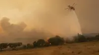 Sebuah helikopter menjatuhkan air ke atas kebakaran hutan di desa Dikela, dekat kota Alexandroupolis, di wilayah timur laut Evros, Yunani, Selasa, 22 Agustus 2023. (AP Photo/Achilleas Chiras)
