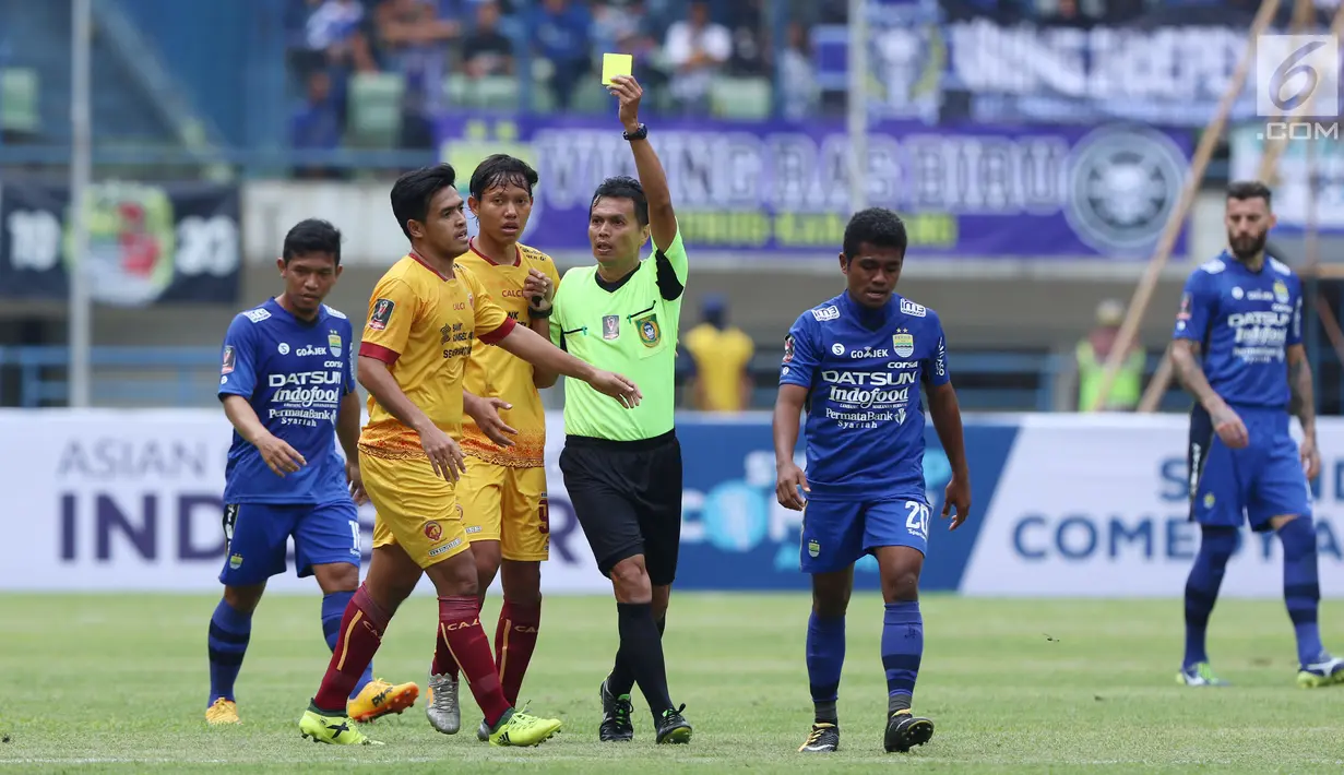 Wasit Jumadi memberi kartu kuning kepada pemain Sriwijaya FC, Novan Setya Sasongko saat laga melawan Persib di laga pembuka Piala Presiden 2018 di Stadion GBLA, Bandung, Selasa (16/1). Persib unggul 1-0. (Liputan6.com/Helmi Fithriansyah)